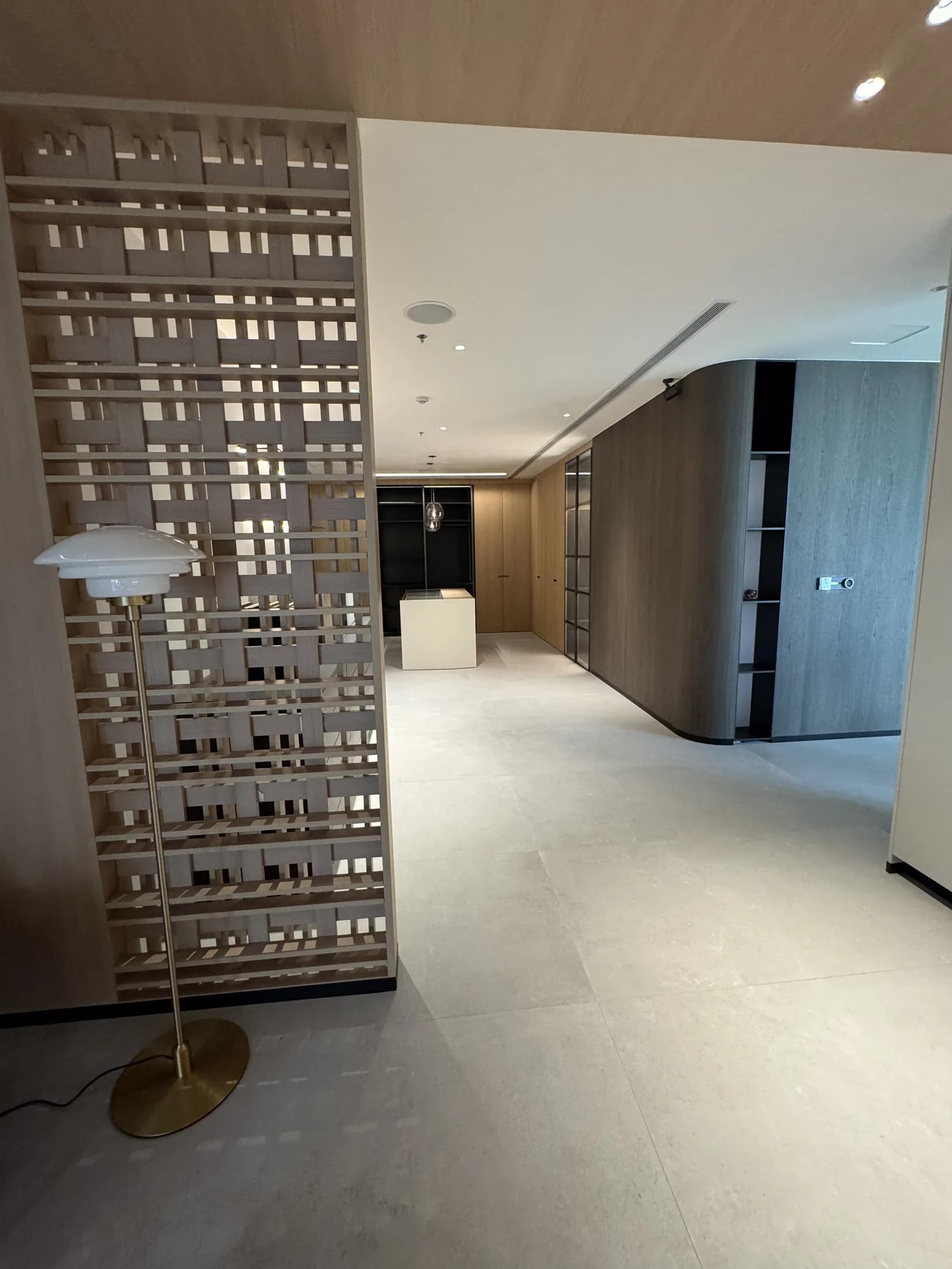Sculptural floor lamp beside a decorative timber lattice screen at the showroom entrance